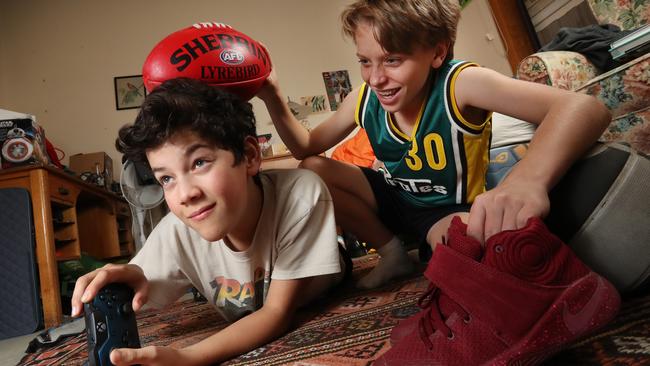 Arleigh plays video games while mate Luke tries to entice him to get active. Picture: Alex Coppel