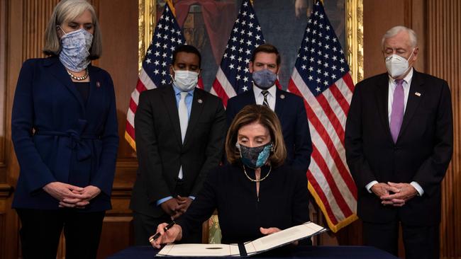 Speaker of the House Nancy Pelosi signs the articles of impeachment alongside impeachment managers. Picture: AFP