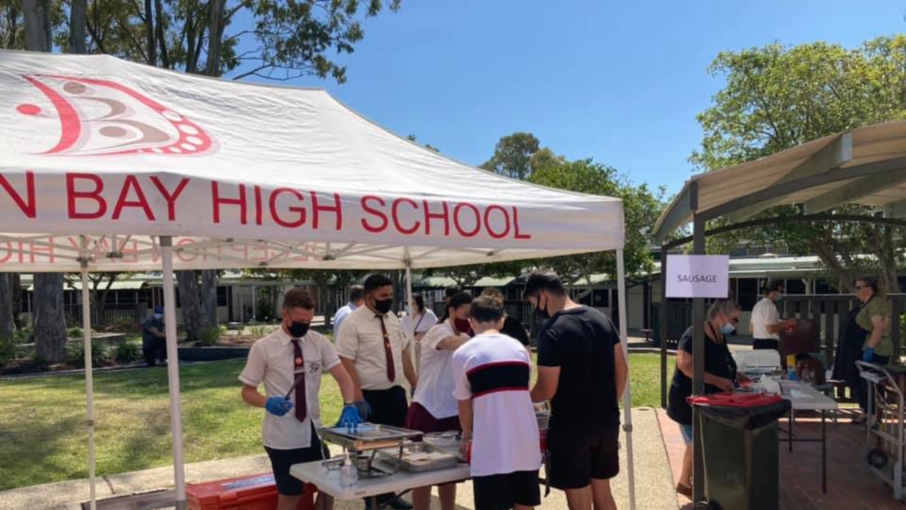 Students hand out sausages at a vaccination clinic at Deception Bay State High School.