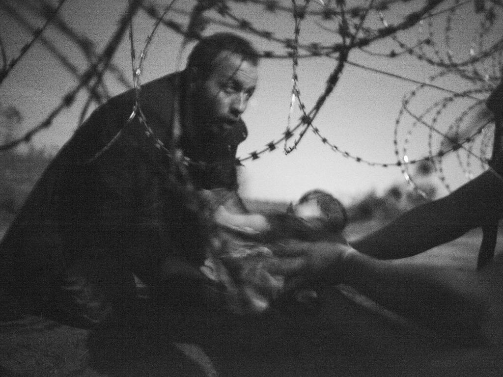 Photo taken by Australian freelance photographer Warren Richardson on August 28, 2015 in Roszke, Hungary, shows a refugee passing a baby under a barbed wire fence at the Hungarian-Serbian border. Titled “Hope for a New Life,” the picture won the prestigious World Press Photo Award on February 18, 2016, highlighting Europe’s worst migrant crisis since World War II. / AFP / WORLD PRESS PHOTO / Warren Richardson / -- RESTRICTED TO EDITORIAL USE - MANDATORY CREDIT “AFP PHOTO / WORLD PRESS PHOTO/ Warren Richardson” - NO MARKETING NO ADVERTISING CAMPAIGNS - DISTRIBUTED AS A SERVICE TO CLIENTS -- NO ARCHIVES - STRICTLY NO SALES --