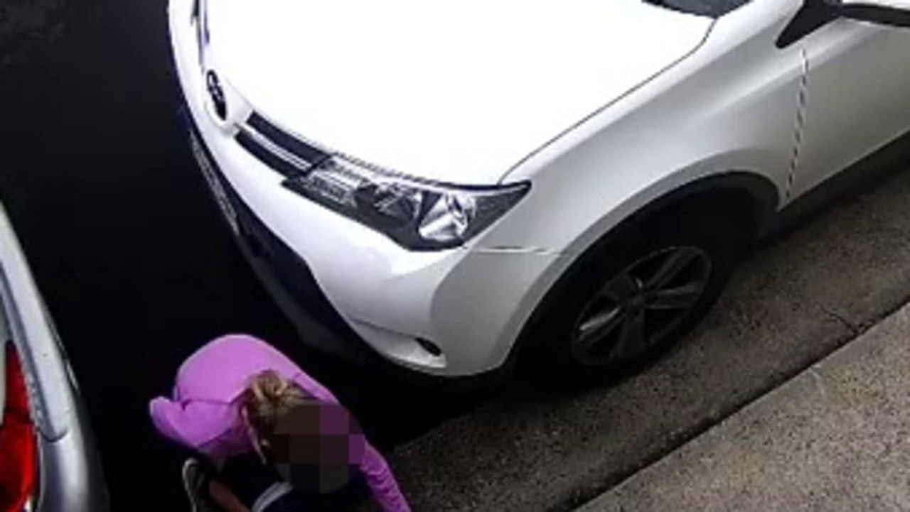 The woman was caught in the act, crouching down between two parked cars.