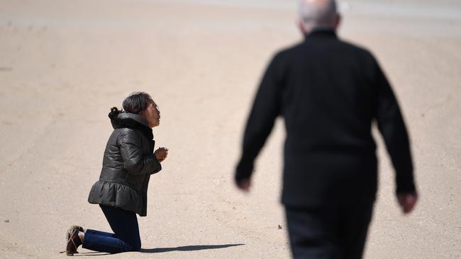 A woman prays on St Kilda Beach in Melbourne on Monday. Picture: AFP