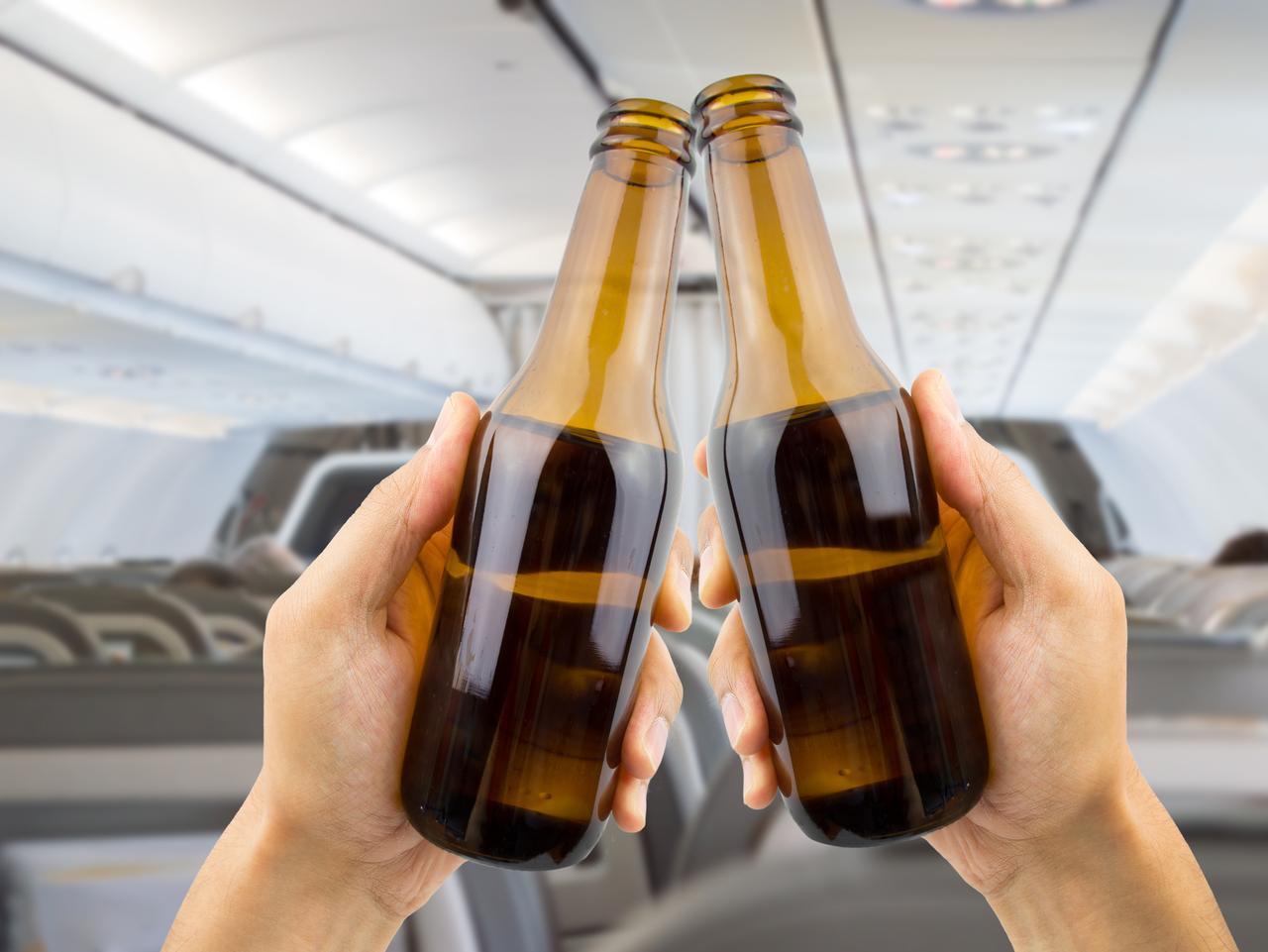 hands raised toasting with beer inside of an airplane