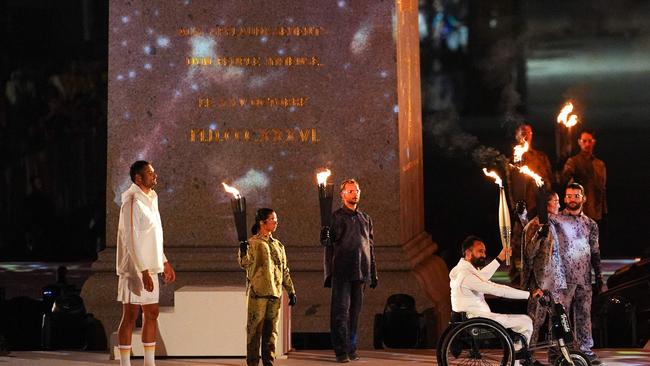 France's wheelchair tennis player Michael Jeremiasz (2nd R) holds the Paralympic flame next to France's Olympic flag bearer Florent Manaudou (L) during the torch relay as part of the Paris 2024 Paralympic Games Opening Ceremony. (Photo by Dimitar DILKOFF / AFP)