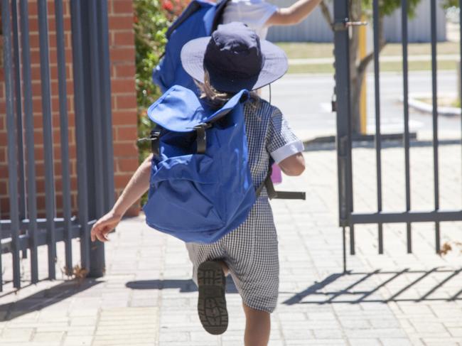 Two school children running out the school gate at the end of the day.