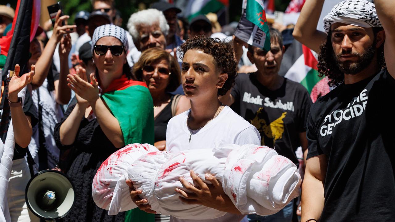 A boy carries towels and bedsheet made to look like the dead body of a child at Hyde Park on November 19. Picture: NCA NewsWire / David Swift