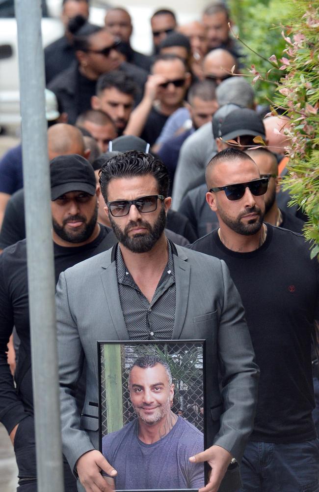 Friends file in to Mick Hawi’s funeral at Al-Zahra Mosque behind a man carrying a photograph of the slain Comanchero. Picture: Jeremy Piper