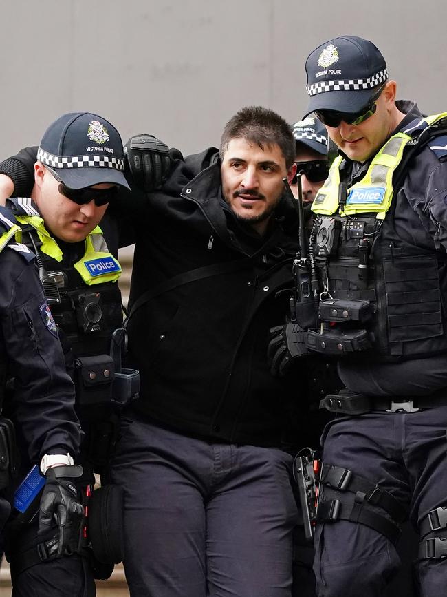 Fanos Panayides is detained by police during a protest outside parliament house in Melbourne on Sunday. Picture: AAP