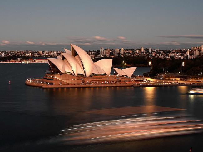 This slow shutter picture shows sunset hues falling on the sails of the iconic landmark Opera House as a ferry makes its way through the harbour in Sydney on June 17, 2021. (Photo by Saeed KHAN / AFP)