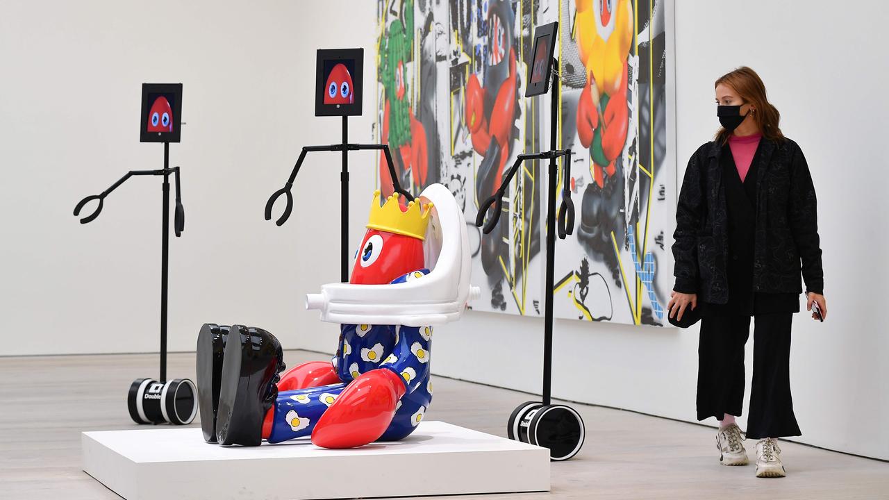 A woman looks at pieces of art alongside remote-view robots that visitors can digitally control to explore the exhibition remotely during a press preview of 'Philip Colbert: Lobsteropolis' at the Saatchi Gallery in London on October 29, 2020. Picture: AFP