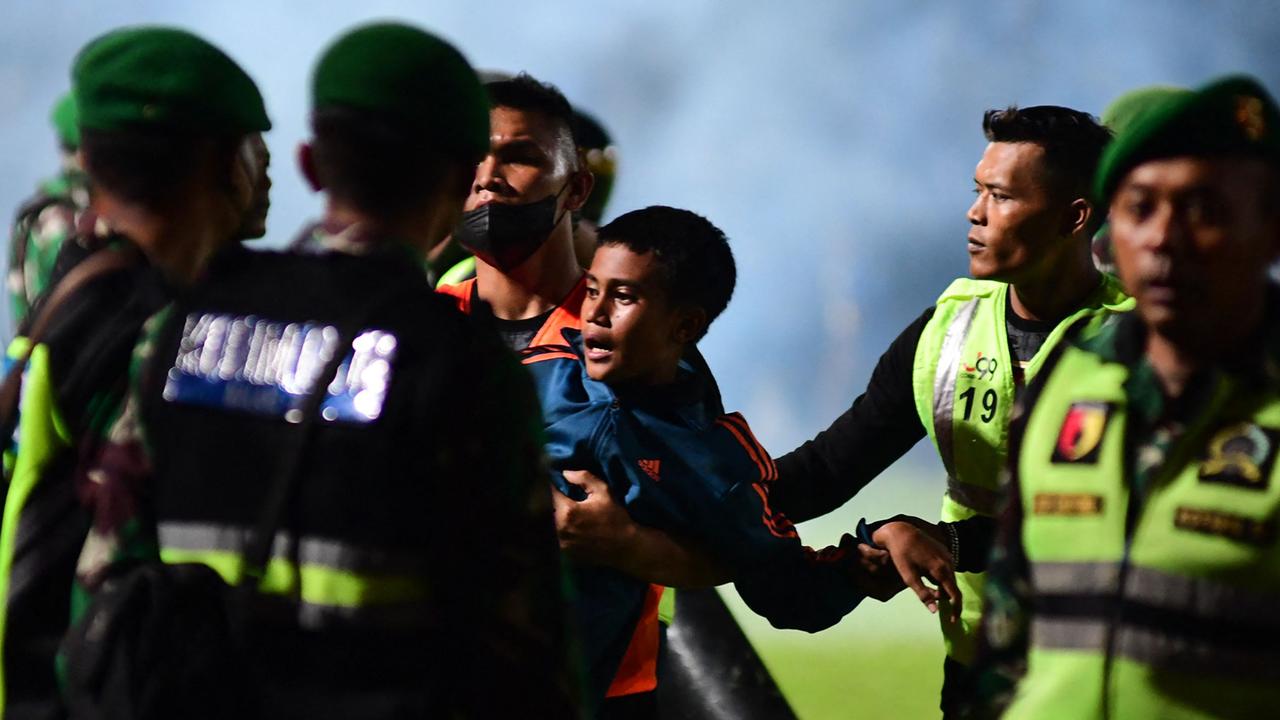 A boy is carried away as members of the Indonesian army secure the pitch after the stampede. Picture: AFP