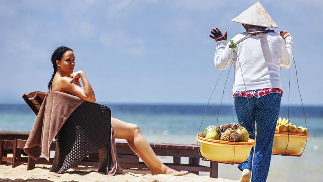 ESCAPE: EATING LOCAL FOOD .. Ian Neubauer story .. PHU QUOC, VIETNAM - APRIL 21, 2014: Vietnamese womans in traditional headdress, which protects from the sun offers fruits for sale to tourists at Long beach on Phu Quoc island, Vietnam. Picture: iStock