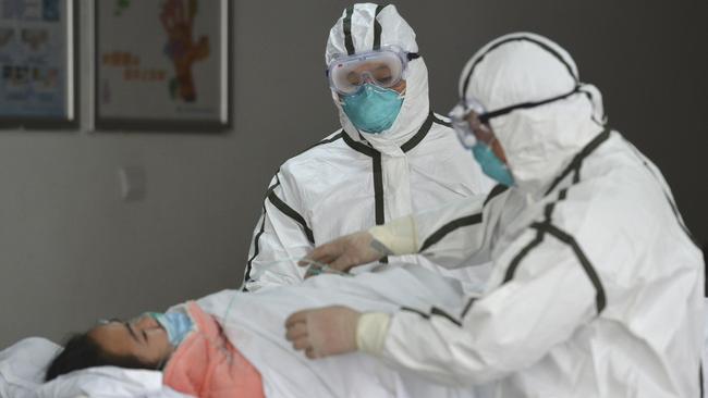 Medical workers in protective suits move a coronavirus patient into an isolation ward at the Second People's Hospital in Fuyang, China. Picture: Chinatopix via AP