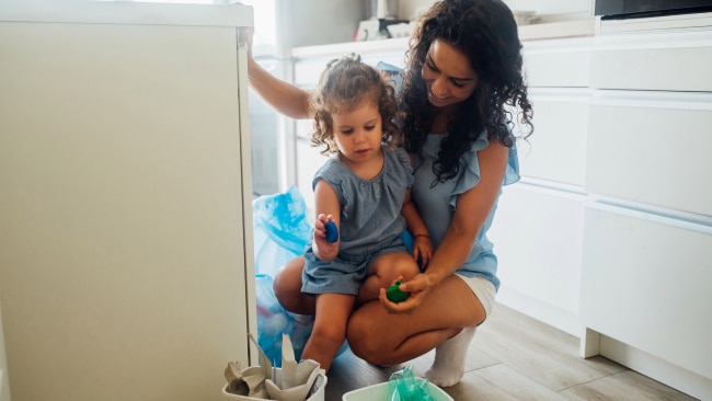 Mother teaching her daughter to recycle