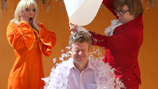 Councillor William Owen-Jones (centre) gets an ice bucket thrown over his head as part of the ALS Ice Bucket Challenge by movie character Austin Powers (right) as his babe looks on at the Movie World, Gold Coast. Picture: Regi Varghese