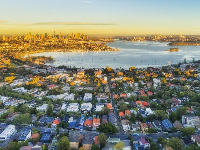 Wealthy Eastern suburbs of Sydney city around Harbour in aerial view with soft morning light and blue sky. Australian housing generic