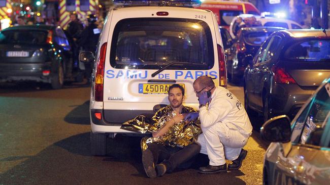 A medic tends to a man in a Paris street.