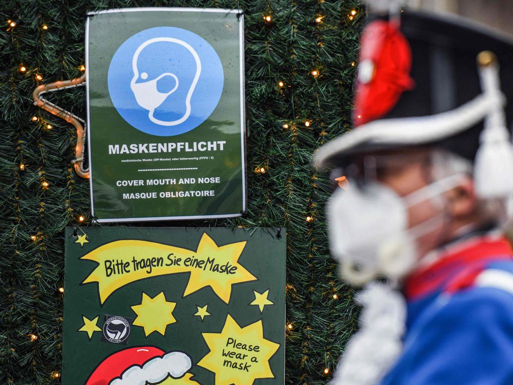 A sign reading "Masks compulsory" and "Please wear a mask" hanging from a decorated tree at a Christmas market in the city of Cologne, western Germany. Picture: AFP