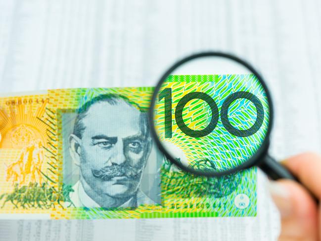 Stock Photo of Australian Money, magnifying glass with $100 note and share market data, tables, investing