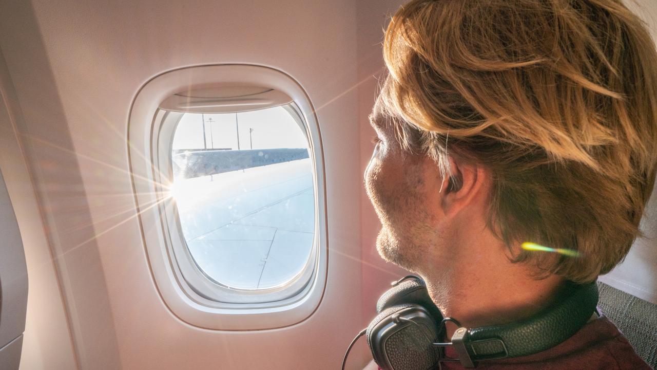 Cheerful young man on aeroplane seat contemplating the outdoors from window. Picture: iStock Kendall Hill, Escape