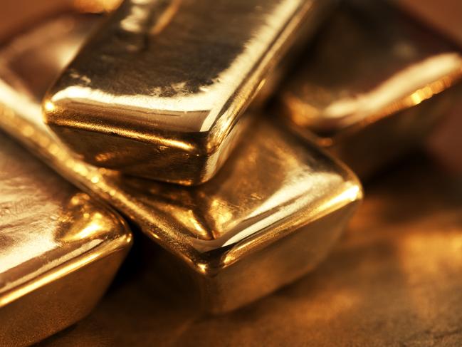 Extreme close up of shiny gold ingots sitting on a dark textured surface