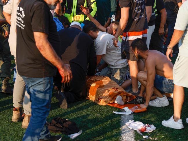 Israeli security forces and medics treat a casualty as local residents gather at a site where a reported strike from Lebanon fell in Majdal Shams village in the Israeli-annexed Golan area on July 27, 2024. (Photo by Jalaa MAREY / AFP)