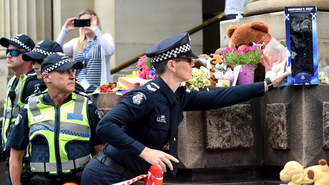 Police members arrive and leave a tribute with message "We're sorry, love Melbourne Highway Patrol”. Picture: Nicole Garmston