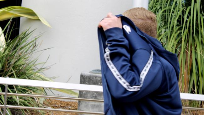 Riley Jae Thompson, 18, of Nerang covers his face outside Southport Courthouse. Picture: Luke Mortimer