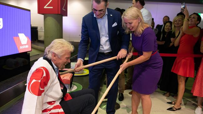 Virgin Australia CEO Paul Scurrah and Queensland Tourism Minister Kate Jones help Sir Richard Branson off the baggage conveyor belt at Brisbane Airport. Picture: Jen Dainer