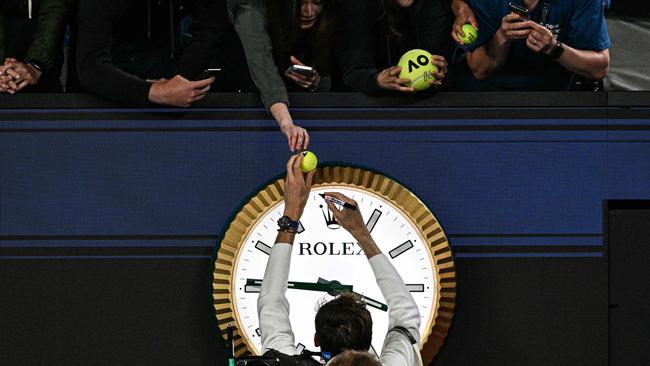 Russia's Daniil Medvedev signs autographs above the clock as he leaves the court after victory against Finland's Emil Ruusuvuori in their men's singles match on day five of the Australian Open tennis tournament in Melbourne early on January 19, 2024. (Photo by Anthony WALLACE / AFP) / -- IMAGE RESTRICTED TO EDITORIAL USE – STRICTLY NO COMMERCIAL USE --