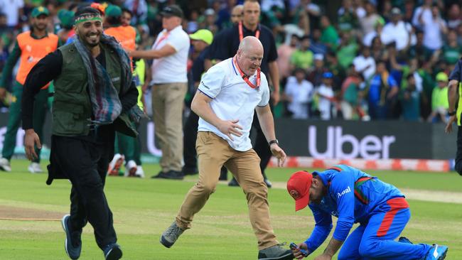 An official (C) assists an Afghan player (R) as a pitch invader (L) runs on the field. Picture: AFP