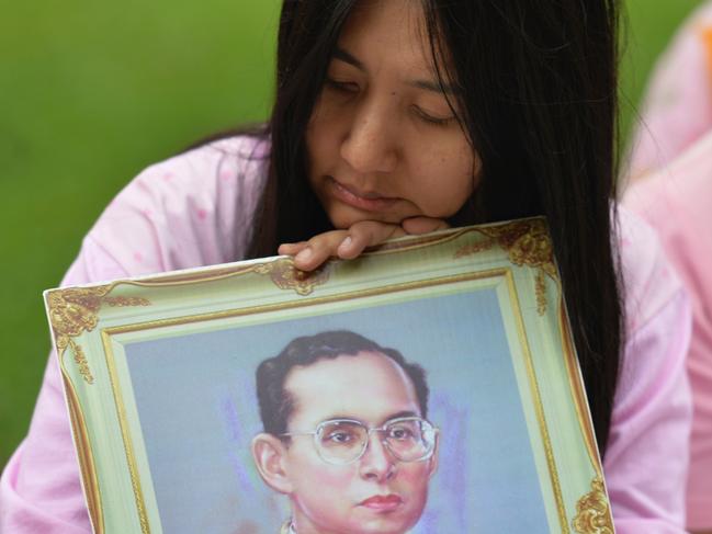 A Thai woman holds a portrait of Thai King Bhumibol Adulyadej as she pray for his health at Siriraj Hospital, where the king is being treated, in Bangkok on October 12, 2016. Thailand's junta chief said he planned to hold talks with the Crown Prince following days of unprecedented concern over the health of ailing King Bhumibol Adulyadej. / AFP PHOTO / MUNIR UZ ZAMAN