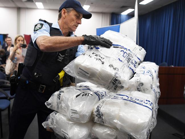 An Australian Federal Police officer places a bag of crystal methamphetamine on a table before a press conference at the AFP headquarters. Picture: David Moir