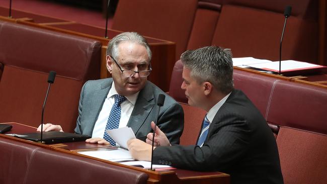 Senator Don Farrell (left) talking with Senator Mathias Cormann in the Senate Chamber, at Parliament House in Canberra.