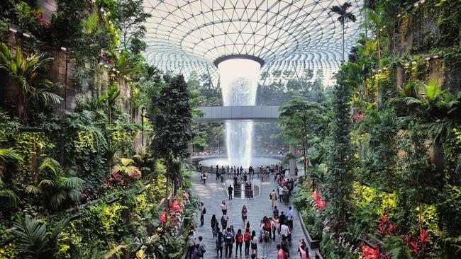 Jewel Changi Airport in Singapore. Visitors tour around the Rain Vortex, the world's tallest waterfall, designed by Moshe Safdie.