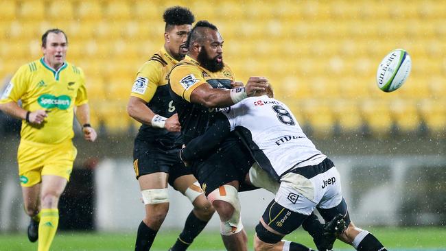 Lone Uhila of the Hurricanes offloads in the tackle of Philip van der Walt of the Sharks.