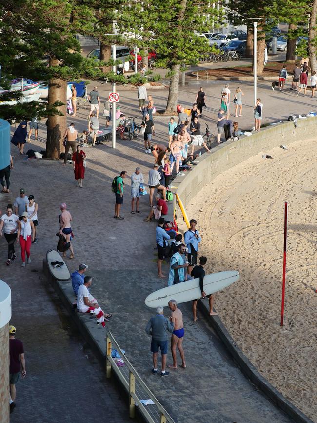 Beachgoers store their belongings on the edge of the beach before heading into the water to swim or surf at Manly. Picture: Matrix