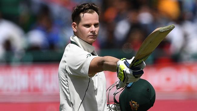 Australia's captain Steve Smith raises his bat and helmet as he celebrates his century.