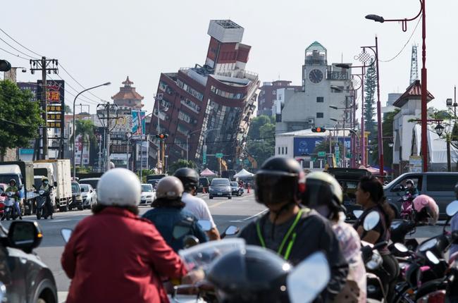 Local residents ride past a damage of building caused by the earthquake in Hualien