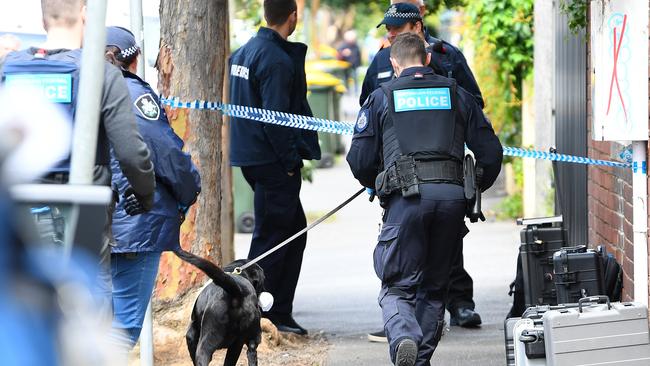 An AFP officer and police dog at a property in Elwood. Picture: AAP Image/James Ross