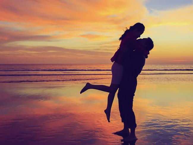 Happy young couple kissing and hugging each other in sunset background