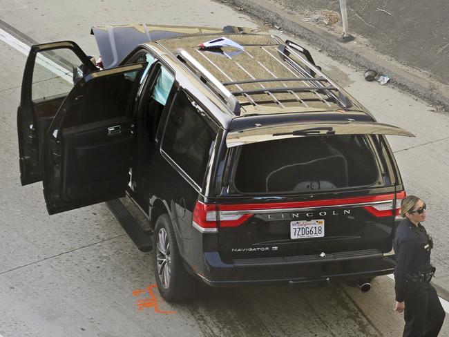 Los Angeles police officers stand after a pursuit of a stolen hearse with with a casket and body inside on Interstate 110 in South Los Angeles Thursday, Feb. 27, 2020.  The hearse was stolen from outside a Greek Orthodox church in East Pasadena on Wednesday night. The Los Angeles County Sheriff's Department says one person is in custody.  (AP Photo/Reed Saxon)