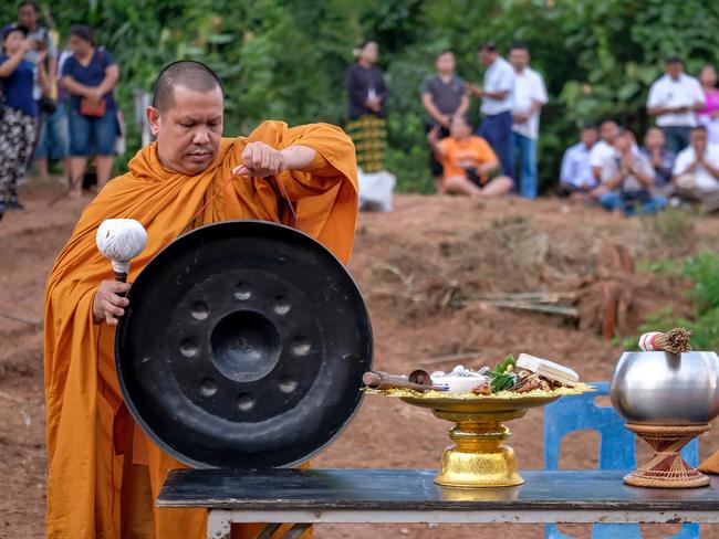 A Buddhist monk holds a praying ceremony at the entrance of Tham Luang Nang Non caves for a successful rescue for the 12 trapped children and their coach. Picture: Getty