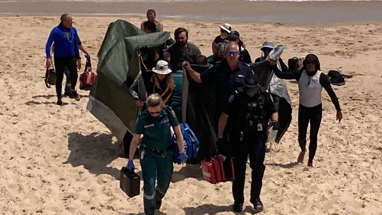 The woman is brought off the beach after reportedly being bitten by a shark. Picture: 7NEWS