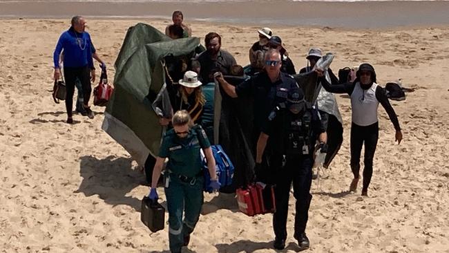 The woman is brought off the beach after reportedly being bitten by a shark. Picture: 7NEWS