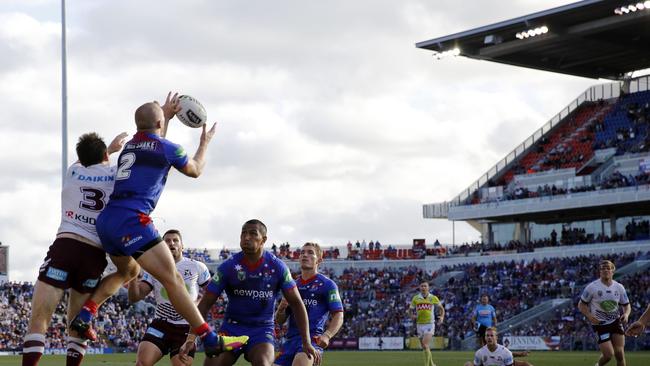 Nathan Ross leaps high to take the ball ahead of Jamie Lyon in the Knights loss to Manly.