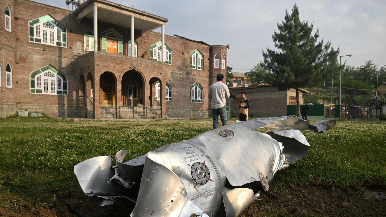 People stand near a part of an aircraft in Wuyan near Indian-administered Kashmir's main city of Srinagar on May 7, 2025. (Photo by TAUSEEF MUSTAFA / AFP)