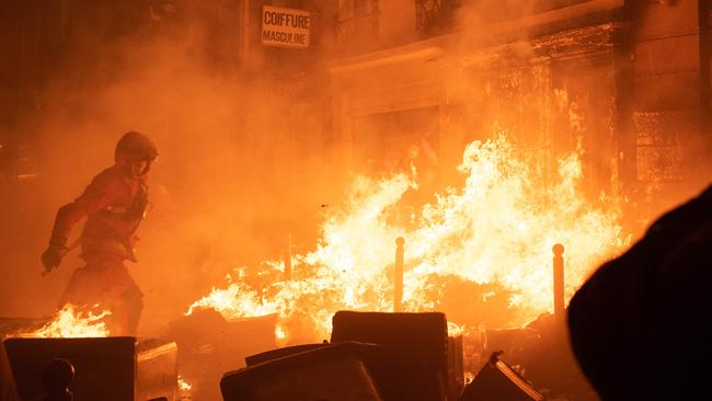 A firefighter tries to extinguish a fire during a demonstration after protesters began lighting garbage on fire in Paris. Picture: AFP