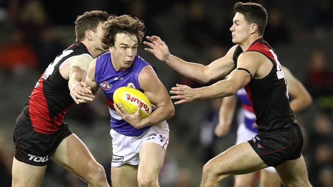 Liam Picken tries to break the tackle of two Essendon defenders.