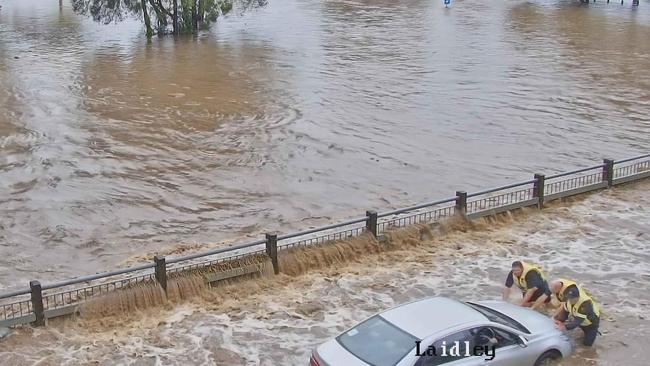 A flood camera captures the moment people attempt to help a driver stranded in floodwaters at Laidley.